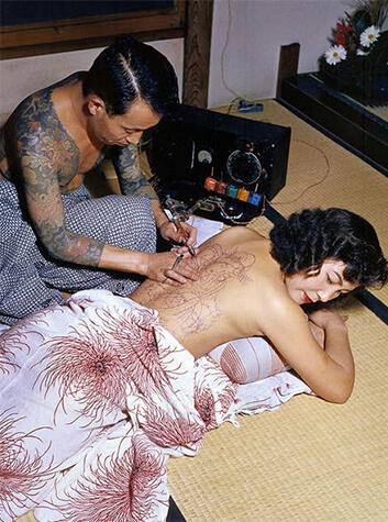 Nghệ sĩ xăm hình Tokumitsu Uchida đang thực hiện Irezumi cho khách hàng nữ vào khoảng năm 1950. Ảnh: buzzfeednews.com